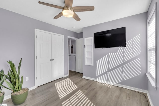 unfurnished bedroom featuring baseboards, multiple windows, a closet, and light wood-style flooring