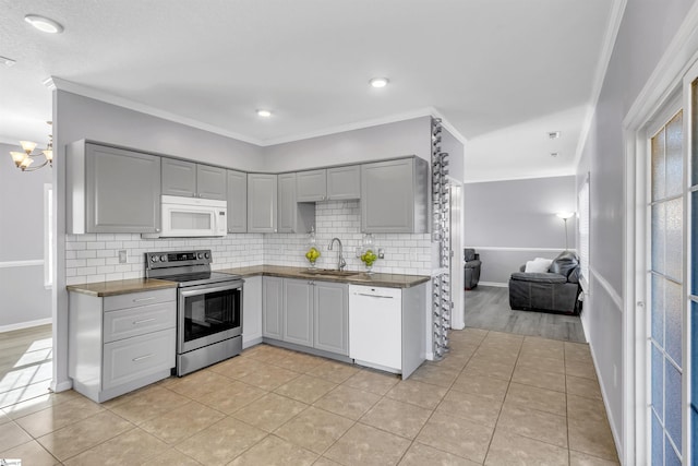 kitchen with white appliances, dark countertops, gray cabinetry, and ornamental molding