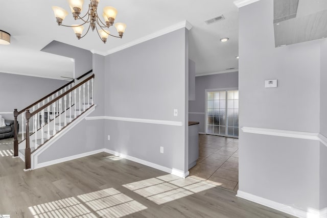 interior space with visible vents, wood finished floors, crown molding, baseboards, and a chandelier