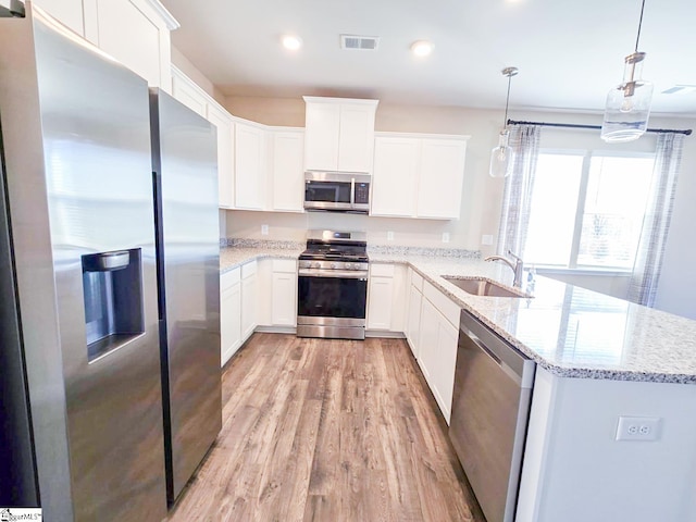 kitchen featuring visible vents, a peninsula, a sink, white cabinets, and appliances with stainless steel finishes