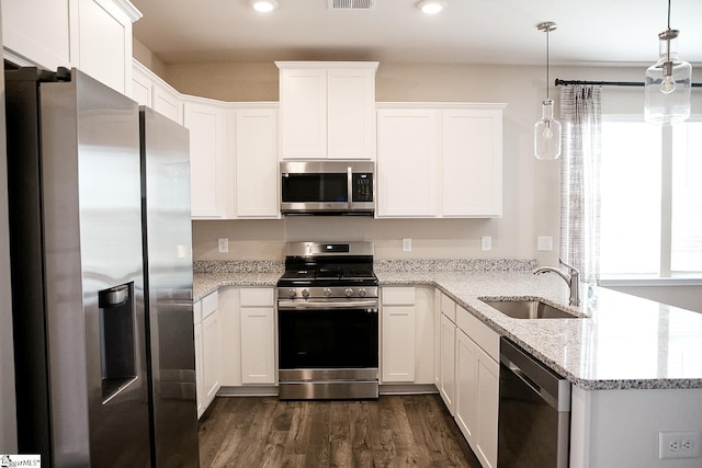 kitchen with a sink, dark wood finished floors, white cabinetry, appliances with stainless steel finishes, and a peninsula