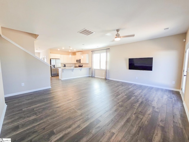 unfurnished living room with a ceiling fan, visible vents, dark wood-style flooring, and baseboards