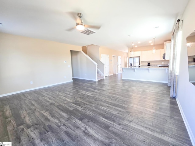 unfurnished living room with baseboards, visible vents, ceiling fan, stairs, and dark wood-type flooring