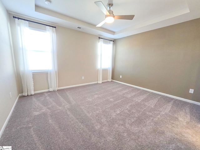 spare room with carpet flooring, ceiling fan, baseboards, and a tray ceiling