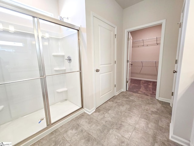 full bath featuring a spacious closet, baseboards, and a stall shower