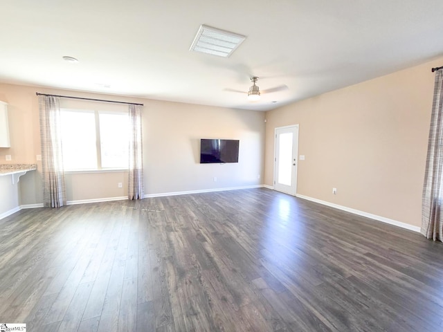 unfurnished living room featuring baseboards, dark wood-style flooring, and ceiling fan