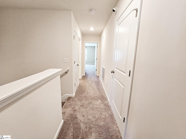 hall with visible vents, an upstairs landing, light colored carpet, and baseboards