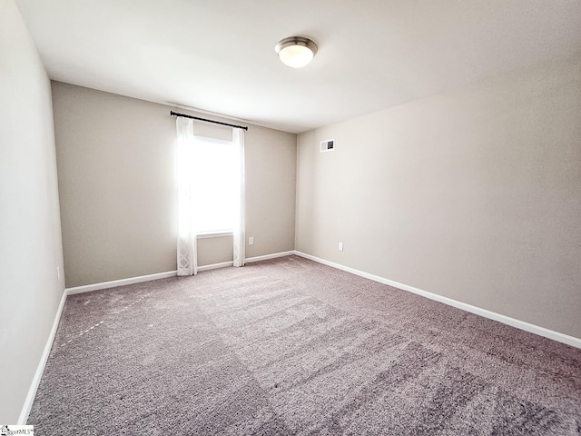 carpeted spare room featuring visible vents and baseboards