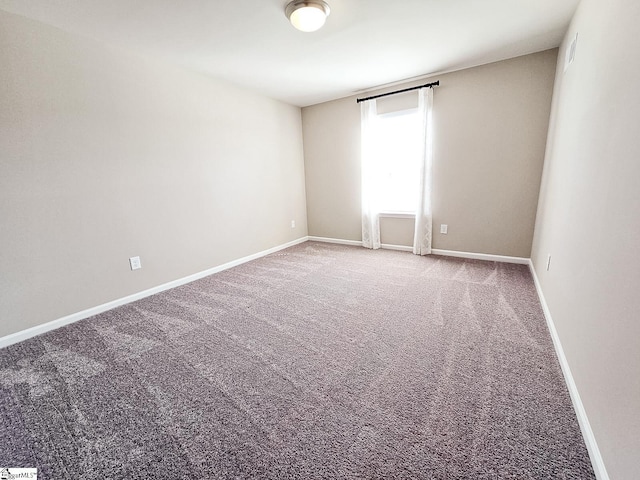 empty room featuring baseboards and carpet flooring