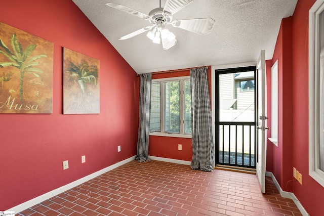 spare room with brick floor, baseboards, ceiling fan, and vaulted ceiling