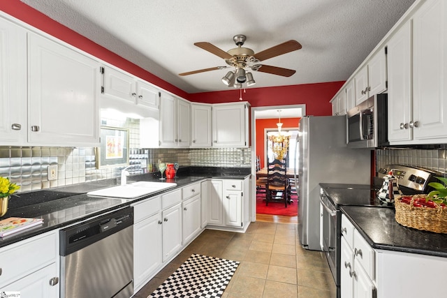 kitchen with decorative backsplash, stainless steel appliances, white cabinetry, a ceiling fan, and a sink