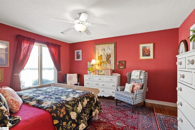 bedroom featuring a ceiling fan, baseboards, wood finished floors, visible vents, and a textured ceiling