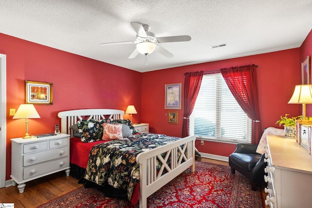 bedroom with ceiling fan, visible vents, a textured ceiling, and wood finished floors