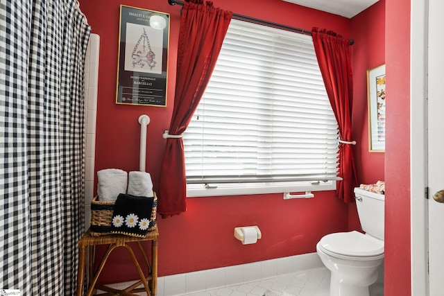 bathroom featuring a shower with shower curtain, baseboards, toilet, and tile patterned flooring