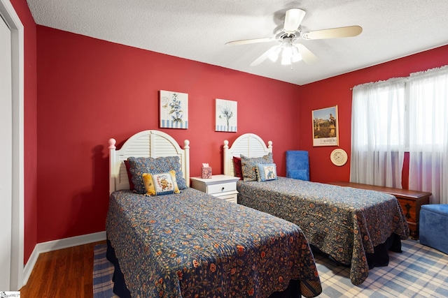 bedroom with baseboards, a textured ceiling, wood finished floors, and a ceiling fan