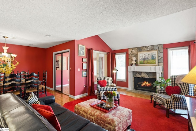 living room featuring vaulted ceiling, a fireplace, wood finished floors, a notable chandelier, and a textured ceiling