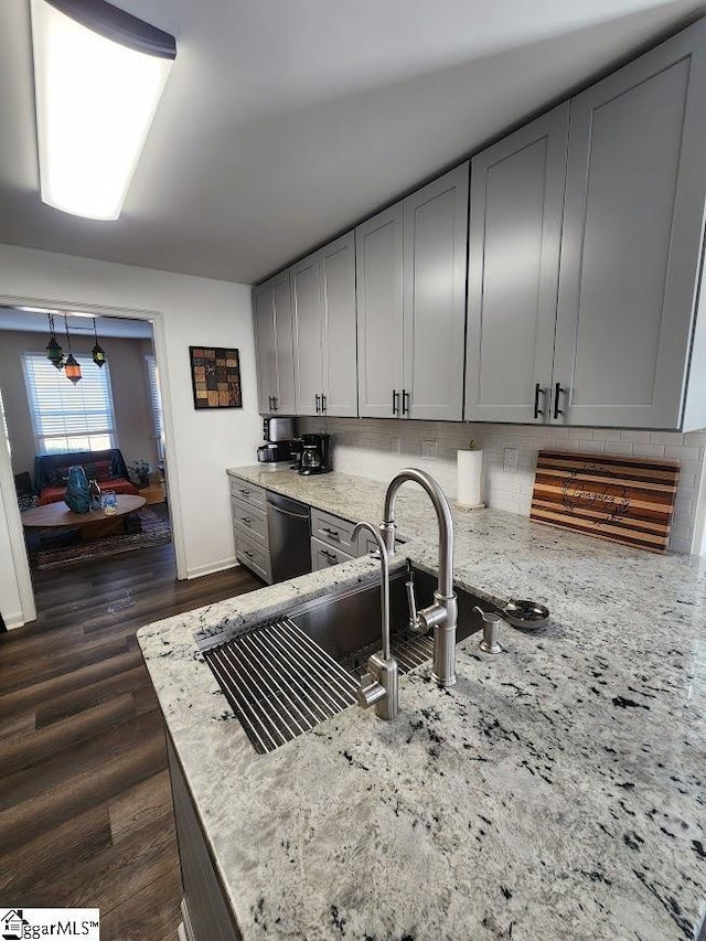 kitchen featuring dishwasher, light stone counters, dark wood-style flooring, and backsplash