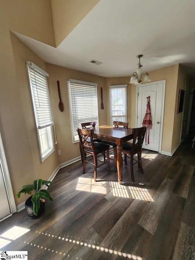 dining area with baseboards, visible vents, dark wood-style flooring, and a chandelier