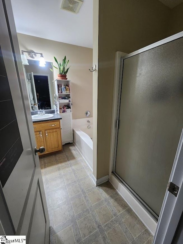 bathroom featuring visible vents, a shower stall, vanity, and a garden tub