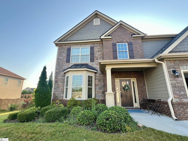 craftsman-style house with fence and stone siding