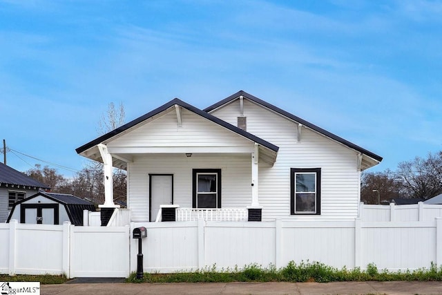 bungalow-style house featuring a fenced front yard, central air condition unit, a porch, and a gate