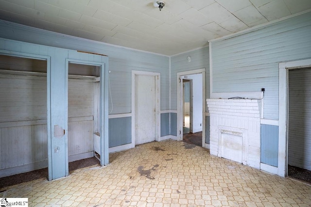 unfurnished bedroom featuring tile patterned floors, multiple closets, and ornamental molding