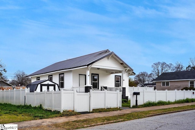 view of home's exterior featuring metal roof, covered porch, a fenced front yard, and a gate