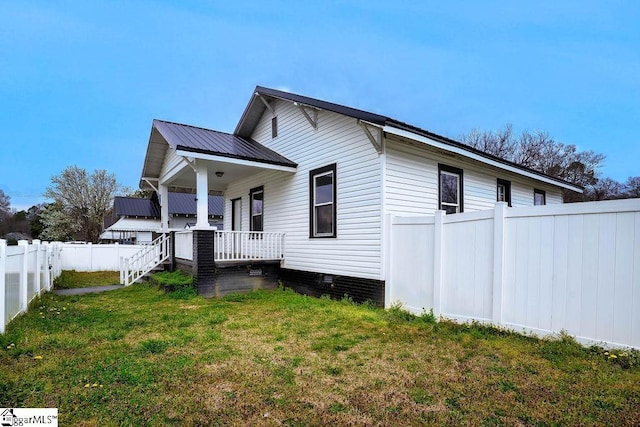 view of side of home with a porch, a yard, a fenced backyard, and metal roof