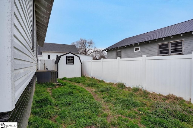 view of yard with a storage shed, an outbuilding, cooling unit, and fence