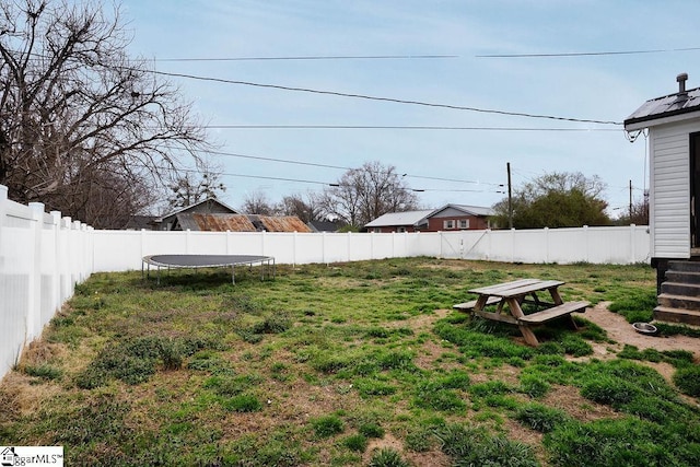 view of yard with a trampoline and a fenced backyard