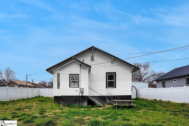 rear view of property featuring a lawn and fence