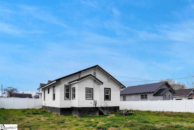 rear view of property featuring a yard and fence