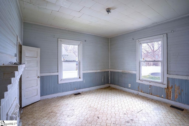 empty room with tile patterned floors, visible vents, and a wealth of natural light