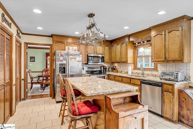 kitchen with a sink, backsplash, stainless steel appliances, brown cabinetry, and crown molding