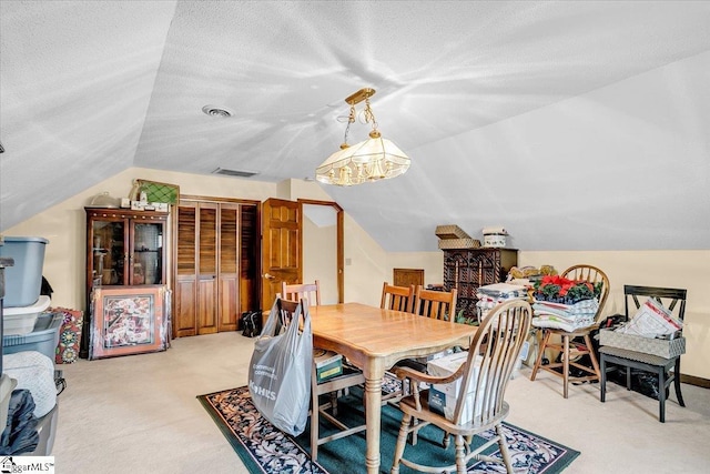 dining area with visible vents, light colored carpet, a textured ceiling, and lofted ceiling