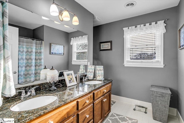 bathroom with a sink, visible vents, baseboards, and double vanity