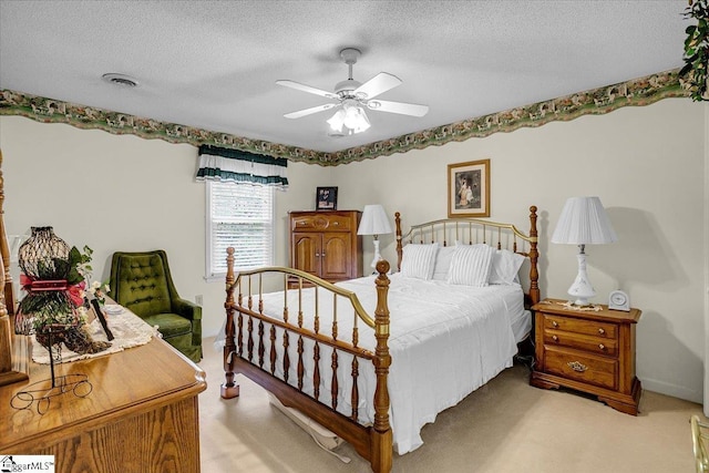 bedroom with ceiling fan, light colored carpet, visible vents, and a textured ceiling