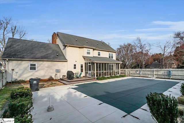 back of house with a wooden deck, a patio, a fenced backyard, and a sunroom