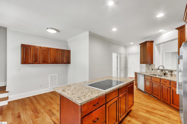 kitchen with light wood-style flooring, a sink, tasteful backsplash, a kitchen island, and stainless steel appliances