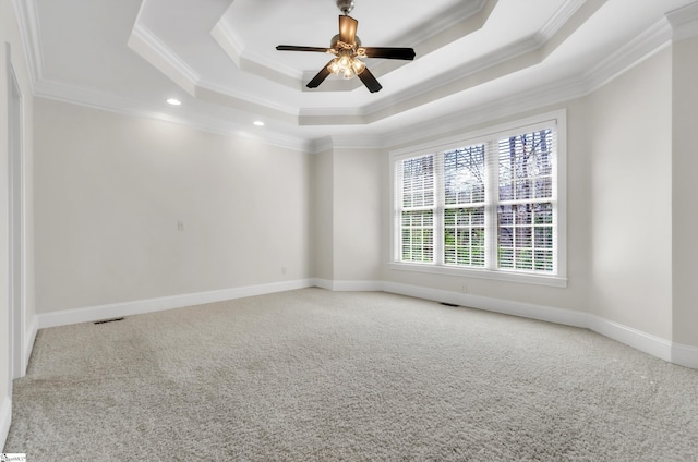 spare room with a tray ceiling, baseboards, carpet, and crown molding