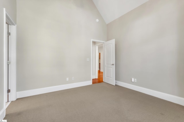 unfurnished bedroom with baseboards, carpet, and high vaulted ceiling