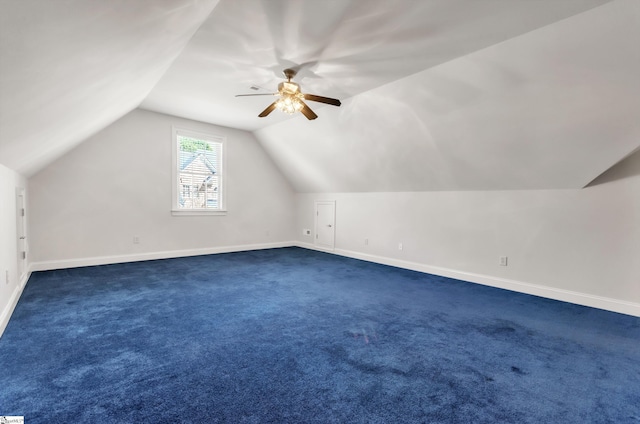 additional living space with dark carpet, baseboards, a ceiling fan, and vaulted ceiling