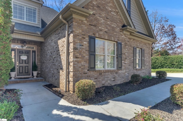 view of home's exterior with brick siding and a shingled roof