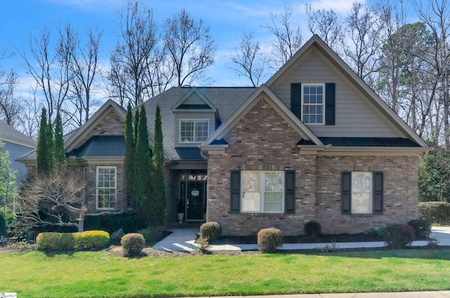 craftsman-style house featuring brick siding, a shingled roof, and a front lawn