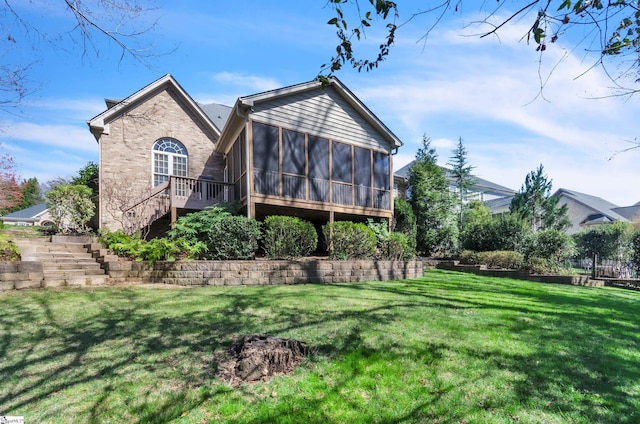 back of house with brick siding, a lawn, stairs, and a sunroom