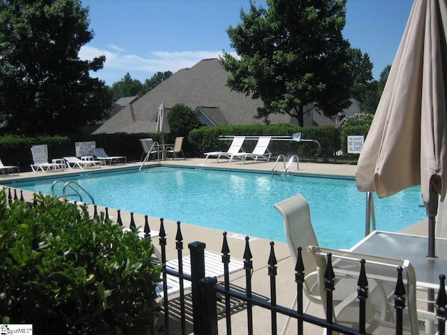 community pool with a patio and fence