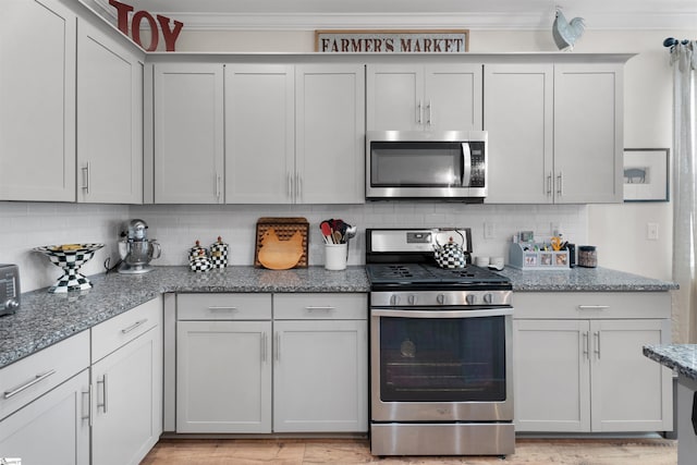 kitchen featuring light stone counters, tasteful backsplash, appliances with stainless steel finishes, and ornamental molding