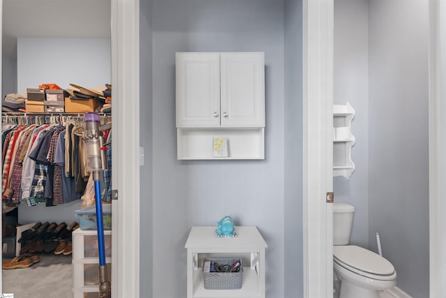 bathroom featuring toilet and a walk in closet