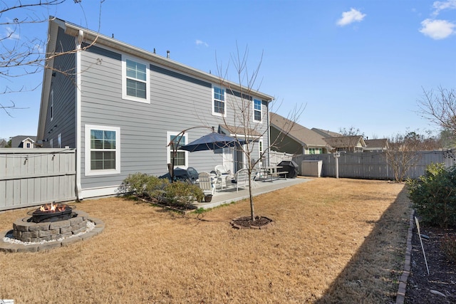 rear view of house featuring a yard, a fenced backyard, an outdoor fire pit, and a patio