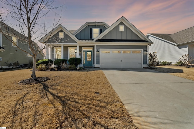 craftsman-style house with board and batten siding, covered porch, a yard, a garage, and driveway